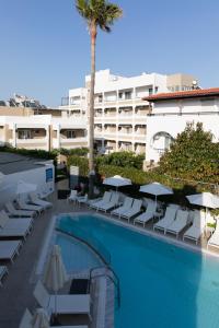 una piscina con tumbonas y un hotel en Agrelli Hotel & Suites, en Kardamaina