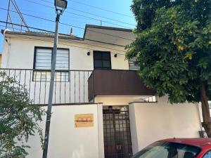 una casa blanca con un coche rojo estacionado frente a ella en Xochimilco Apartment, en Oaxaca City