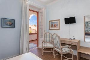 um quarto com 2 cadeiras, uma secretária e uma televisão em Borgo Prima Luce em Cuglieri