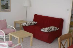 een woonkamer met een rode bank en 2 tafels bij Appart 801, Tennis village in Cap d'Agde