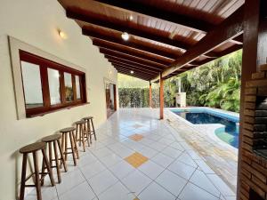 an outdoor patio with stools and a swimming pool at Casa com piscina privativa no Paúba um Vilarejo in São Sebastião