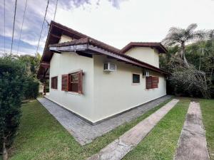 Biały dom z brązowymi okiennicami i ogródkiem w obiekcie Casa com piscina privativa no Paúba um Vilarejo w mieście São Sebastião