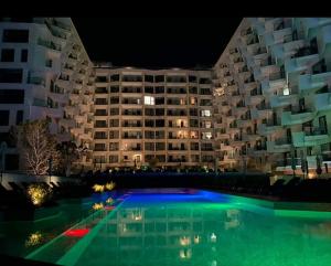un gran edificio de apartamentos por la noche con piscina en Alee Infinity Pool & Spa by Black Sea en Mamaia-Sat
