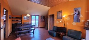 een woonkamer met oranje muren en een bank bij Spacious mountain view attic apartment in Barzio
