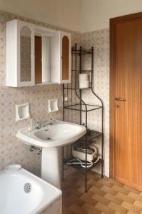 La salle de bains est pourvue d'un lavabo et d'une étagère avec un miroir. dans l'établissement Spacious mountain view attic apartment, à Barzio