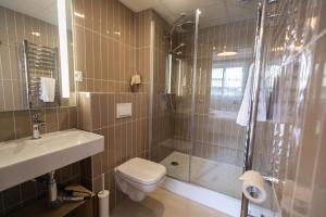 a bathroom with a shower and a toilet and a sink at Hôtel de la Baie in Crozon