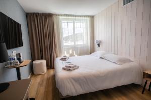 a hotel room with a large white bed and a window at Hôtel de la Baie in Crozon
