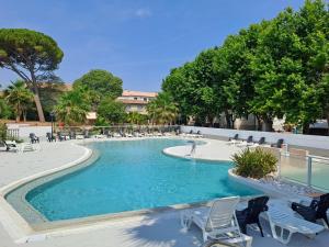 une grande piscine avec des chaises et des arbres dans l'établissement Joli Mobil Home, à Agde