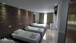 a room with three beds and a brick wall at hotel nacional palace in Foz do Iguaçu