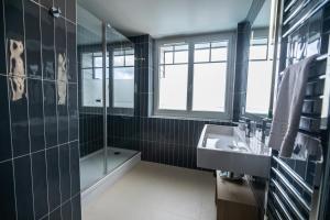 a black bathroom with a sink and a shower at Hôtel de la Baie in Crozon
