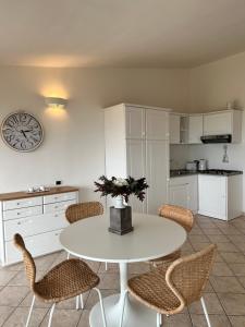 una cucina con tavolo, sedie e orologio di Sardegna Costa Corallina Appartamento Luxury Vista Mare in splendido villaggio - IUN R6511 a Costa Corallina