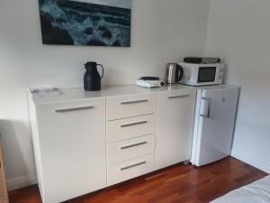 uma cozinha com um frigorífico branco e um micro-ondas em Stort værelse med tekøkken, tæt på hav og fjord. em Bedsted Thy