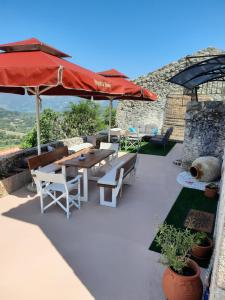 een patio met een tafel en stoelen en een parasol bij Manto's House Lefkada in Évyiros