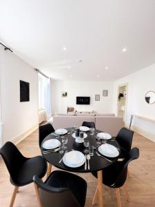 comedor con mesa negra y sillas en Appart'Hôtel Le Jaurès - Jardin privé et Netflix, en Belfort