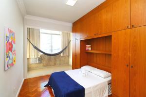 1 dormitorio con cama, armarios de madera y ventana en Rio Spot Homes Copacabana U041, en Río de Janeiro