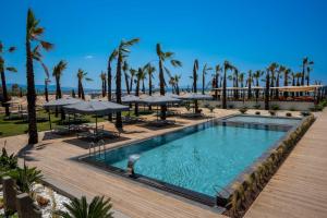 a swimming pool with palm trees and umbrellas at Ayvalık Sea Long in Ayvalık