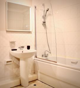 a white bathroom with a sink and a shower at Mathus Gardens in Cambridge