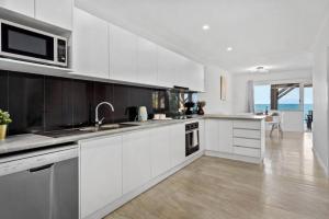 a white kitchen with a sink and a microwave at Sunrise Two Bedroom Apartment in Redcliffe