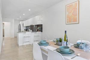 a white kitchen and dining room with a table and chairs at Sunrise Two Bedroom Apartment in Redcliffe