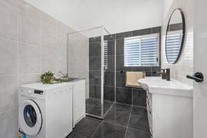 uma casa de banho com uma máquina de lavar roupa e um lavatório em Bay Vista Two Bedroom Waterfront Apartment em Redcliffe