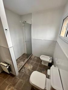 uma casa de banho com um chuveiro, um WC e um lavatório. em Moderno y tranquilo departamento em El Calafate