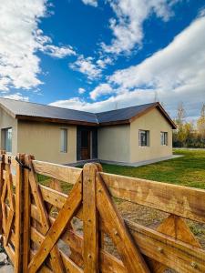 uma cerca de madeira em frente a uma casa em Moderno y tranquilo departamento em El Calafate