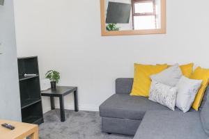 ein Wohnzimmer mit einem grauen Sofa und gelben Kissen in der Unterkunft WhereToStay Entire 2bed House in Barrow in Furness