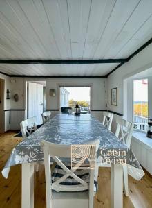 a dining room with a table and white chairs at Southern cottage with terrace and magnificent view in Lillesand