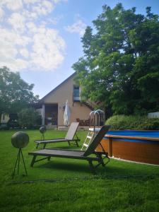 a couple of lounge chairs sitting in the grass next to a pool at Gere House in Siófok