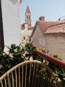 un balcón con una planta y una torre del reloj en Apartments & Rooms Trogir Stars FREE PARKING en Trogir