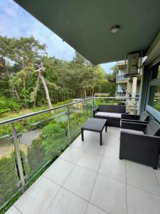 a balcony with couches and a view of trees at Cappuccino by OneApartments in Jurata