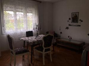 a dining room with a table and chairs and a window at Apartman Brzak in Zagreb