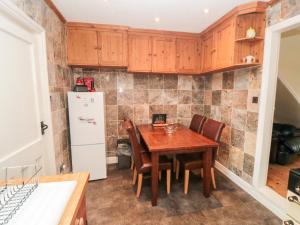 a kitchen with a wooden table and chairs and a refrigerator at Sunnyside Cottage in Filey