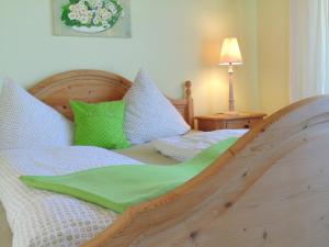 sypialnia z drewnianym łóżkiem z zielonymi i białymi poduszkami w obiekcie Allgäu Sonne w mieście Oberstdorf