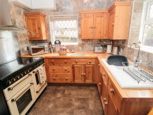 a kitchen with wooden cabinets and a stove at Sunnyside Cottage in Filey