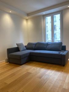 a blue couch in a living room with a window at Super appartement refait à neuf beaucoup de charme in Boulogne-Billancourt