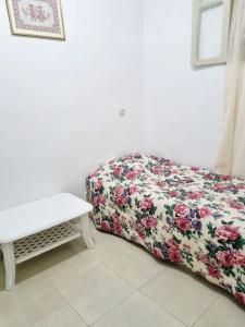 a bed with a floral blanket and a table at Maison l'océan in Rabat