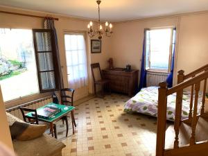 a bedroom with a bed and a table and windows at Les Pommiers, Bouilland in Bouilland