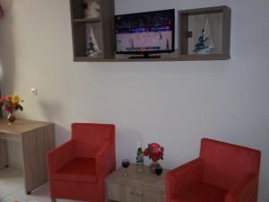 2 sillas rojas en la sala de estar con TV en Stalaktites Studios, en Sami
