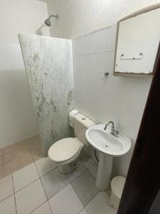 a white bathroom with a toilet and a sink at Pousada Saint Germain in Búzios