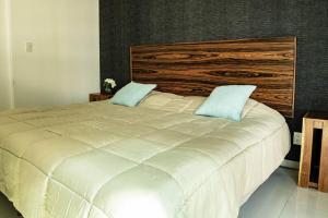 a large white bed with two blue pillows on it at Lovely Apartment with Rooftop, Pool & Gym in CDMX in Mexico City