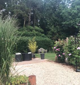 a garden with a bench and some bushes and trees at The Cheese Room, self-contained cosy retreat in the Quantock Hills in Bridgwater