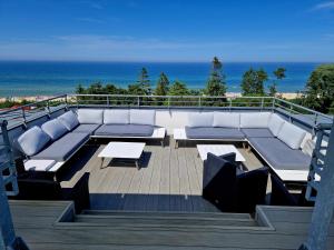 a balcony with couches and tables and the ocean at Atrium Oaza Sarbinowo in Sarbinowo