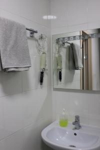 a white bathroom with a sink and a mirror at Apartment on Chernyakhovskogo 5V in Vladivostok