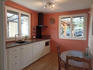 uma cozinha com um lavatório, uma mesa e 2 janelas em Studio chemin de Saint Jacques em Vals-près-le-Puy
