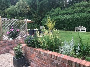 a garden with a brick retaining wall and flowers at The Cheese Room, self-contained cosy retreat in the Quantock Hills in Bridgwater