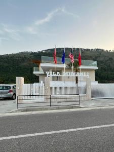 una recinzione bianca con tre bandiere di fronte a un edificio di Apartaments Vila Mimani 2 a Berat
