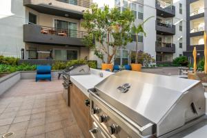 a barbecue on a patio with a building in the background at Exclusive Suites in MDR-Venice with Pool, GYM & HotTub in Los Angeles