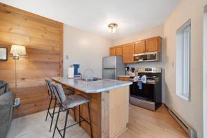 a kitchen with a counter with chairs and a counter top at Hidden Valley Condo at Resort- Walk to Slope, Golf, Hike in Somerset