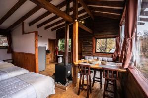 a bedroom with a bed and a kitchen with a stove at Cabañas Borde Rio Las Trancas in Nevados de Chillan